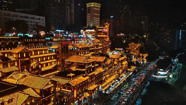 Hongya Cave glowing above the riverside road in Chongqing at night