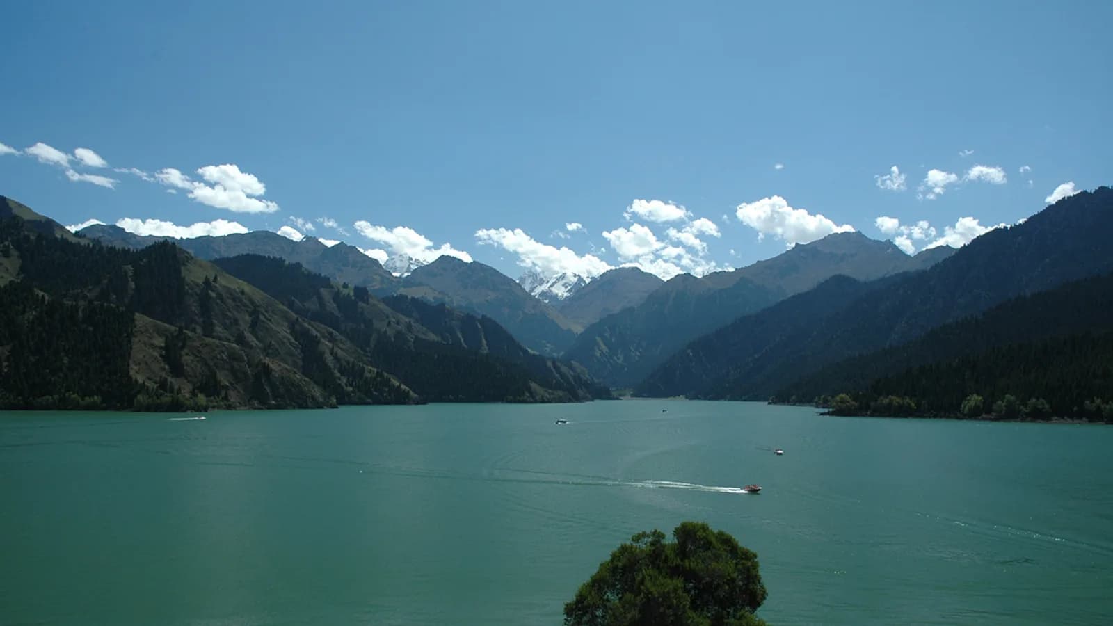 A summer road crossing the open grasslands and mountains of Xinjiang